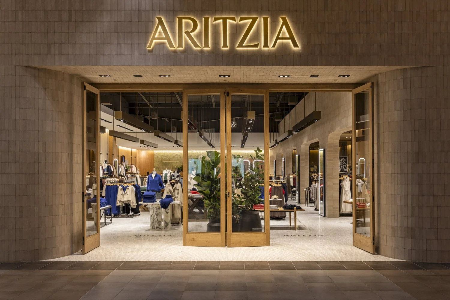Aritzia storefront in Salt Lake City, with illuminated signage and timber-framed entrances