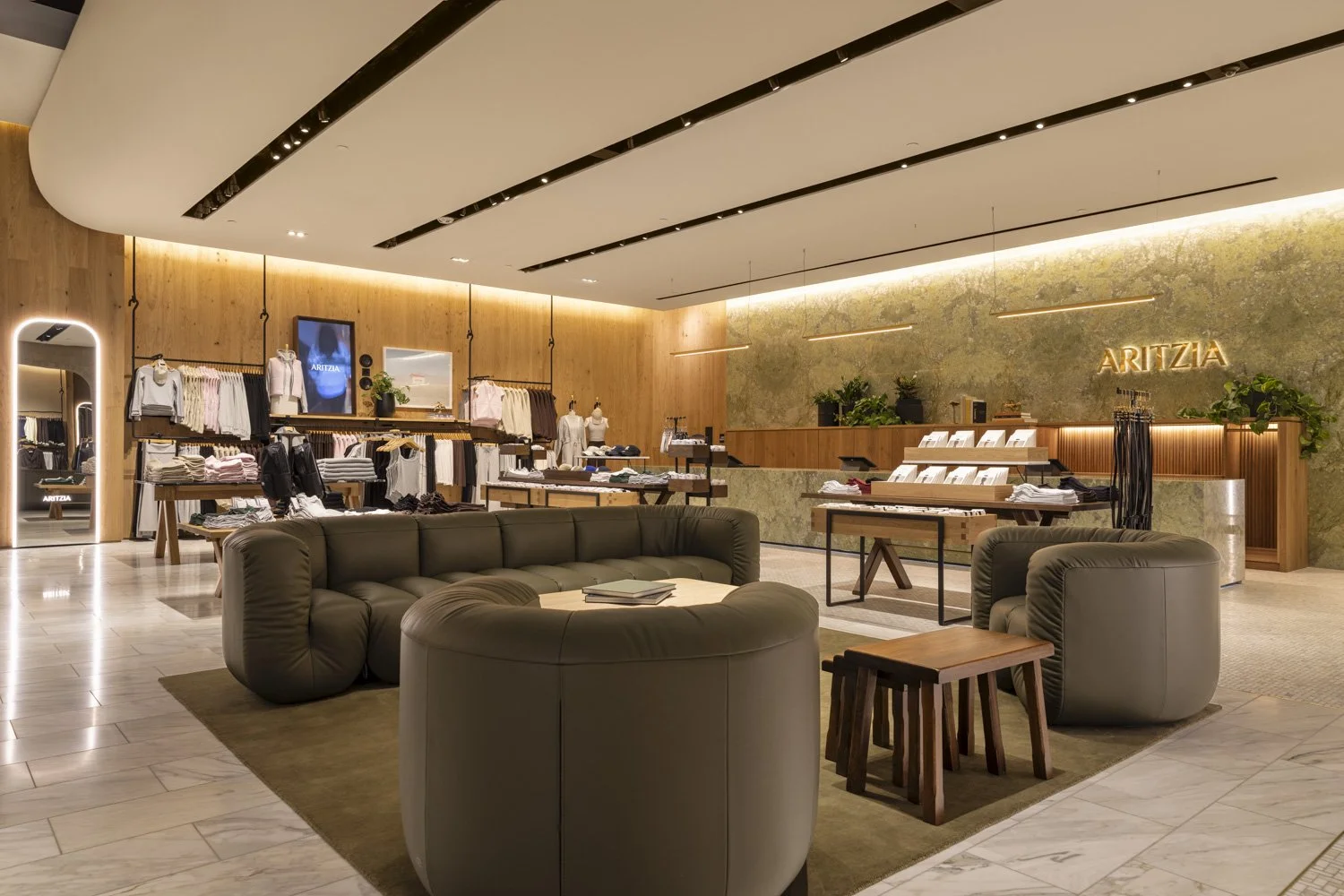 Curved lounge seating beside clothing displays and the stone checkout counter at Aritzia, Salt Lake City
